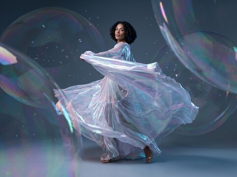 Woman in Iridescent Dress Surrounded by Floating Bubbles
