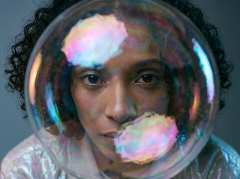 Person Inside Iridescent Bubble Against Gray Background