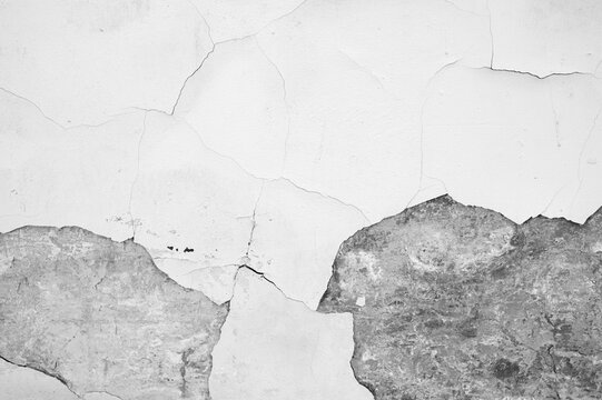 Cracked plaster wall surface with textured damage and fine lines showing underlying roughness.