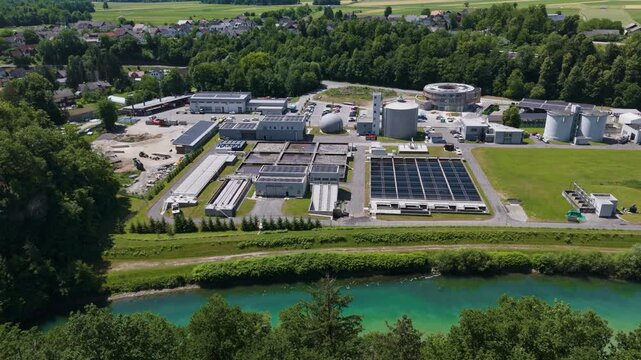 The picture shows a large wastewater treatment plant with settling tanks and filtration systems.