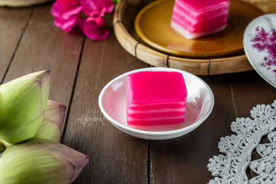 Traditional Southeast Asian pink layered sweet cake, known as Khanom Chan in Thai or Kueh Lapis in Malay culture, served on a green plate, representing authentic Peranakan culinary heritage.