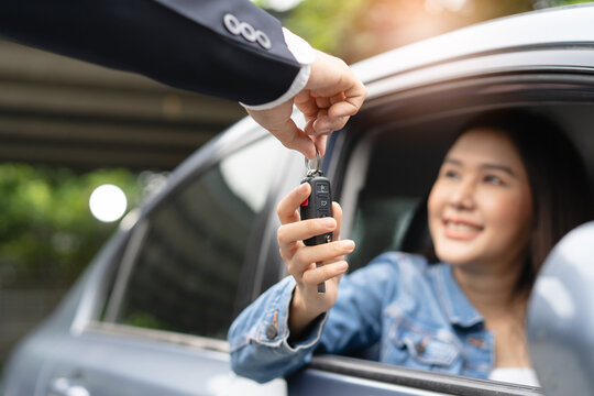 transportation rental automotive business concept. Close up hands of rental auto agent giving car remote key to client to travel sightseeing.