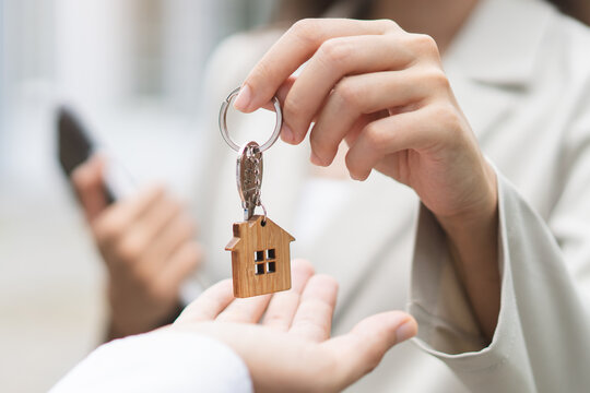 Close up view realtor broker holding home keychain in her hand.
