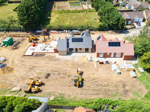 Interesting drone UAV view of a new detached bungalows being built within a small building plot in Cambridgeshire, UK. Established homes surround the site.