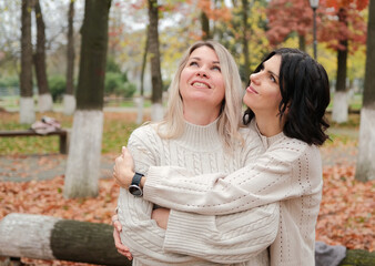 Fototapeta premium two female friends hugging in autumn park, emotional support