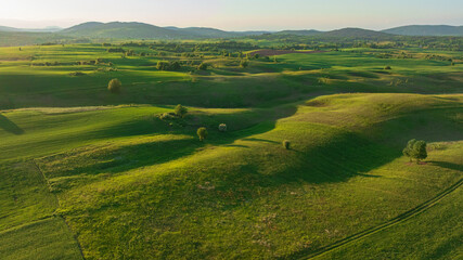 Naklejka premium Drone shot displays rural landscape of Dreznik area near Plitvice Lakes. Green agricultural fields, farm lands, and countryside roads spread across traditional Croatian village territory.