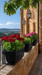 Fototapeta premium Flower boxes on a black metal balcony enhance the historic stone building in bright sunlight with green foliage and a distant landscape