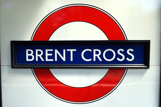 The sign for the London Underground at Brent Cross station, on the Northern Line, showcases the traditional roundel design consisting of a red circle and blue bar against a white backdrop.