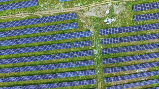 Aerial view solar panel arrays stretching across green field, systematic rows, drone scanning, engineer planning maintenance, metallic blue panels glinting