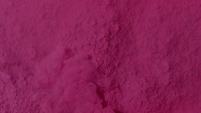 View from above macro shot of a stream of pink dispersion flowing in a petri dish over a pile of powder