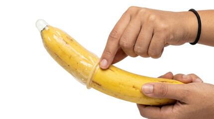 Hands rolling a latex condom onto a fresh yellow banana © BTG