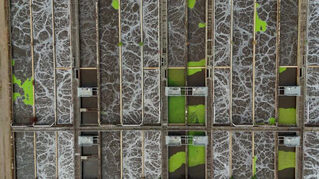Top-down aerial view of active aeration lanes with bubbling activated sludge at a wastewater treatment works