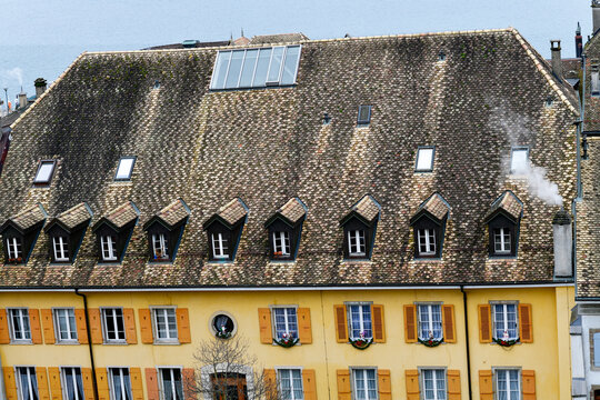 Historisches Geb&auml;ude mit einer markanten Reihe von Dachgauben und ockergelber Fassade in Nyon, Schweiz