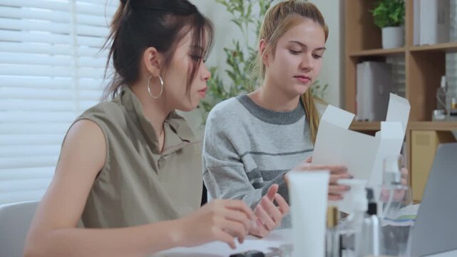 Cosmetic bottle packaging marketing design review Two colleagues discuss rd stage plan with cosmetic bottles and box mockup on desk with laptop and natural light for product strategy