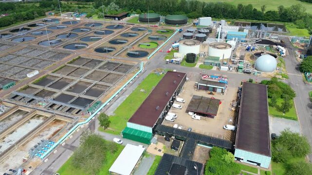 Wastewater sewage plant with large sedimentation tanks and anaerobic digesters, close up aerial view, Milton Keynes, UK.