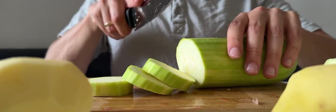 Slicing fresh zucchini on wooden cutting board, healthy vegetables, cooking ingredients, home kitchen