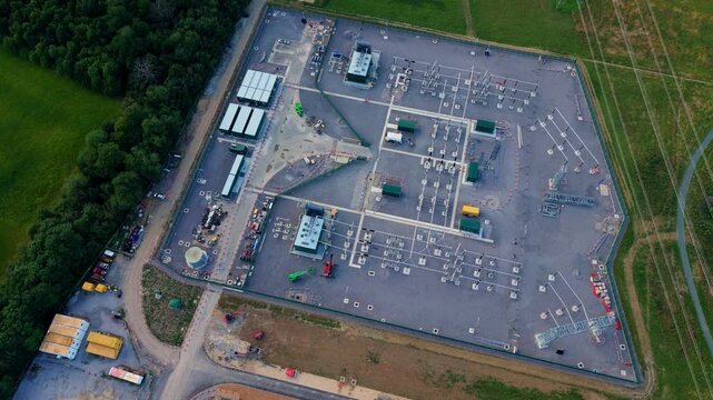 Aerial view of a massive electrical substation with switchgear units, busbars, and high-voltage power lines in Biggleswade, UK.