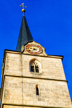 Der historische gotische Kirchturm mit farbenpr&auml;chtiger Turmuhr der Stadtpfarrkirche St. Johannes der T&auml;ufer in Kronach, Bayern