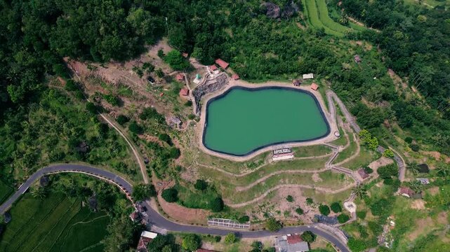 Aerial drone footage of Embung Nglanggeran, a scenic artificial reservoir located in the Ancient Nglanggeran Volcano area, Yogyakarta, Indonesia.