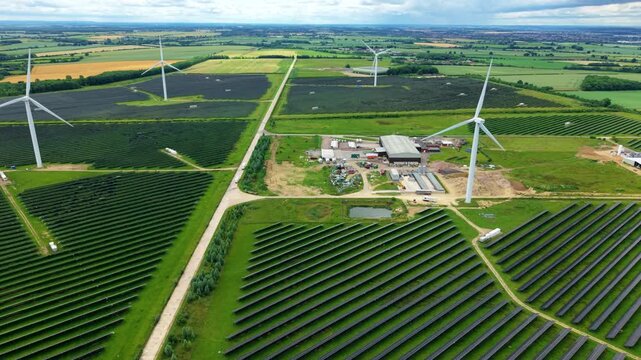 Aerial view of a massive hybrid solar and wind energy farm in rural England for net zero power resilience