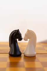 Black and white chess knight pieces standing face to face on chessboard, business competition concept. © Александр Ланевский