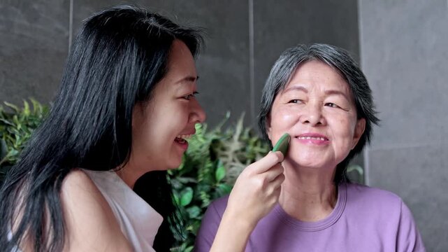 Daughter massaging her mother's face with a gua sha stone