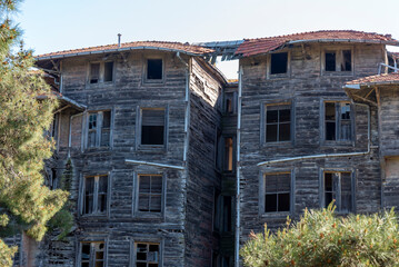 Fototapeta premium Old wooden building with damaged roof and broken windows in a deserted area during daylight hours