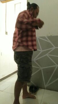 Man in Plaid Shirt and Shorts Standing Indoors.