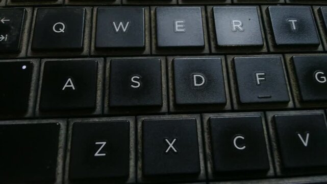 Close-up of a dark computer keyboard with illuminated keys.