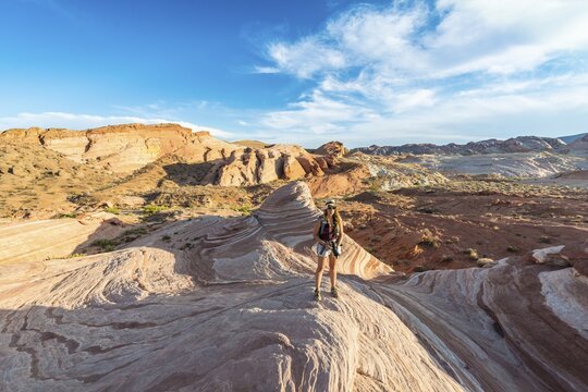 Tourist, hiker at the Fire Wave Sandstone Formation, behind Sleeping Lizard rock formation, Valley of Fire State Park, Nevada, USA