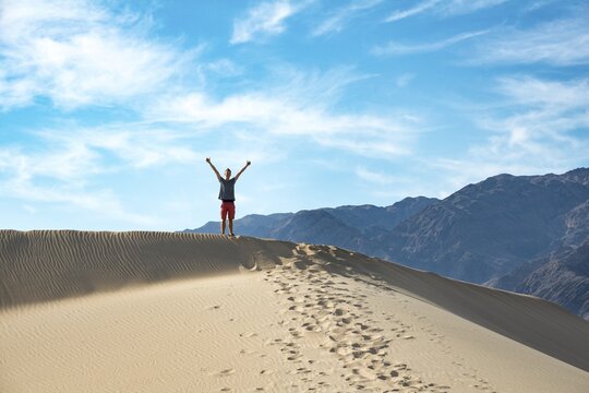 Young man standing on sand dune, Mesquite Flat Sand Dunes, Death Valley, Death Valley National Park, California, USA