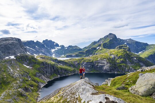 Two hikers looking into camera, lake Tennesvatnet, mountain landscape, Moskenes&ouml;y, Lofoten, Nordland, Norway