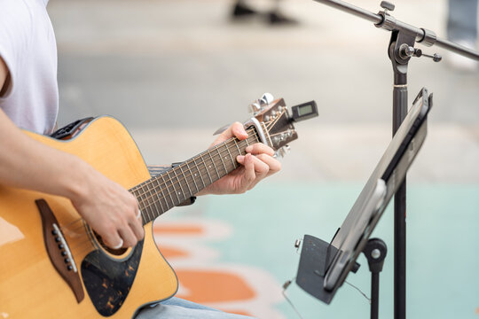 outdoor street performer playing acoustic guitar scene