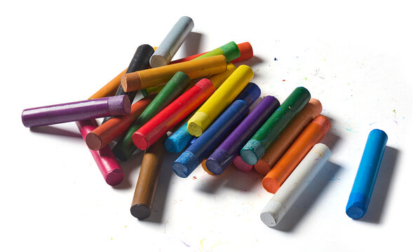 scattered messy colorful oil pastels isolated white background paper surface, dirty wax crayons piled together with color marks, top view