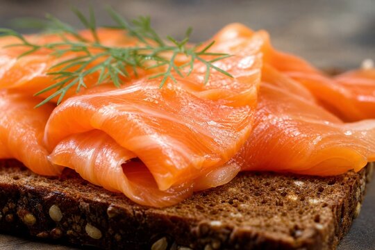 Close-up of oily smoked salmon slices on dark rye bread.
