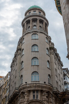 Historic building with round tower and windows in urban area during cloudy day