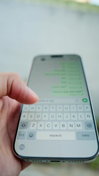 Close-up of a hand holding a modern smartphone and typing on the virtual keyboard