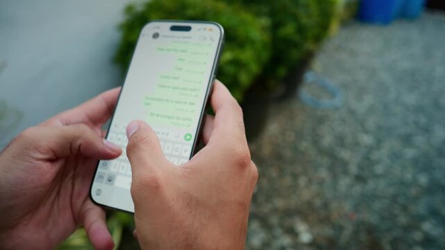 Close up of male hands typing and sending a text message on a smartphone using an app