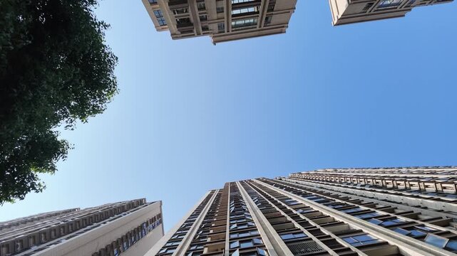 low angle view of urban high rise residential buildings with clear blue sky and green trees