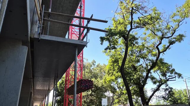 Video of a tower crane lowering a bundle of engineered timber I-joists very close to the frame of a modern residential house under construction.
