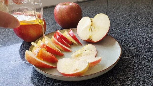 Man hand pouring honey on apple slices for rosh hashanah celebration