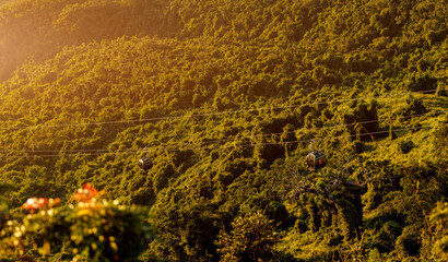 Cable car gondola suspended over green hillside at sunset Sanya, Hainan Island, China © Parilov