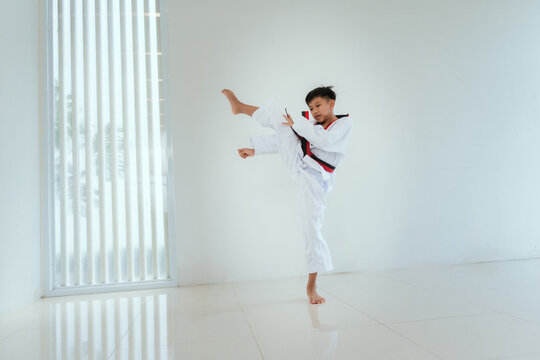 Young person practices martial arts moves in a bright training space during the day
