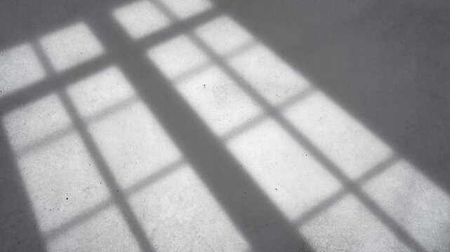 Gray concrete texture background with window frame shadow.Abstract minimalist background of a gray concrete or cement floor surface with a sharp window frame shadow overlay. 
