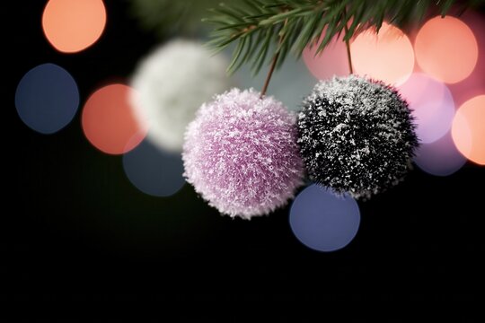 Colorful decorations hanging on green branches in winter with blurred lights in the background