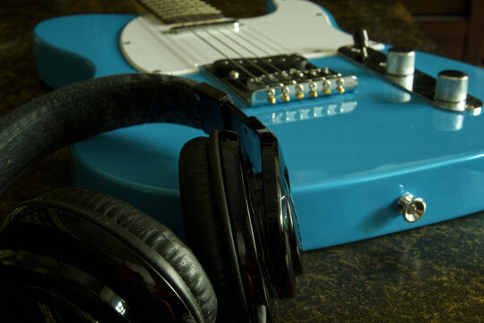 Blue electric guitar and black headphones resting together, representing music lifestyle and sound