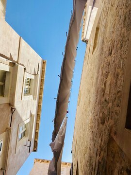 White bedsheets drying on clotheslines in the narrow streets of Dubrovnik&rsquo;s old town, swaying between stone buildings in warm Mediterranean light