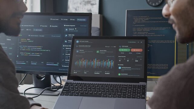 Cropped shot of Indian young male developers sitting at desk in front of PC and laptop and analyzing software in modern office. Perfect for IT consulting and customer service technology promos