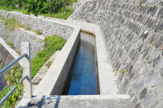 Concrete irrigation canal with stone retaining walls.