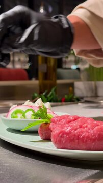 Close-up of a chef seasoning kibbeh nayyeh with ingredients